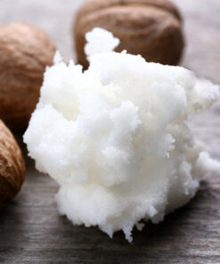 White shea butter with shea nuts behind it to the left, on a grey wood