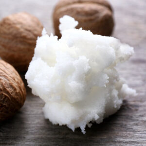 White shea butter with shea nuts behind it to the left, on a grey wood